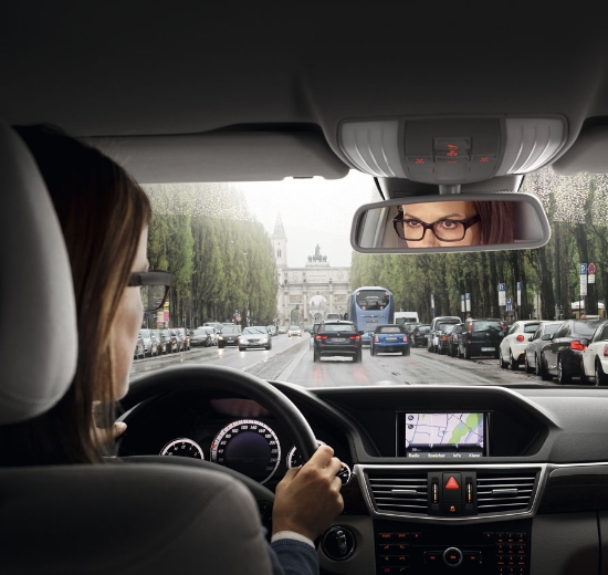 Blick über die Schulter einer Autofahrerin mit Brille.